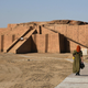 A woman approaches a large Sumerian ziggurat.